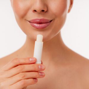 Woman applying lip balm for smooth lips.