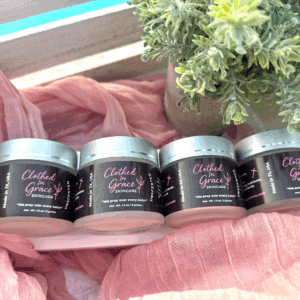 Skincare jars on pink fabric with plant.